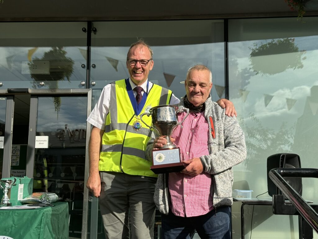 A photo of Councillor Nigel Yates presenting the winner of the Council's Classic Vehicle Show, John Cook, with the trophy cup on the Town Hall steps