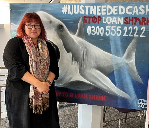 Photo of the Chief Officer, Mrs Sarah Haydon, in front of the Stop Loan Sharks Display Board in the Town Hall in October 2023