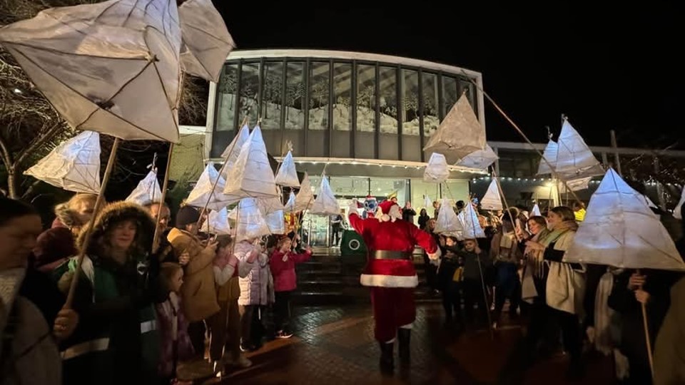 Santa Claus arriving at the Town Hall with the lanterns lined up either side of him as he goes up the Town Hall steps