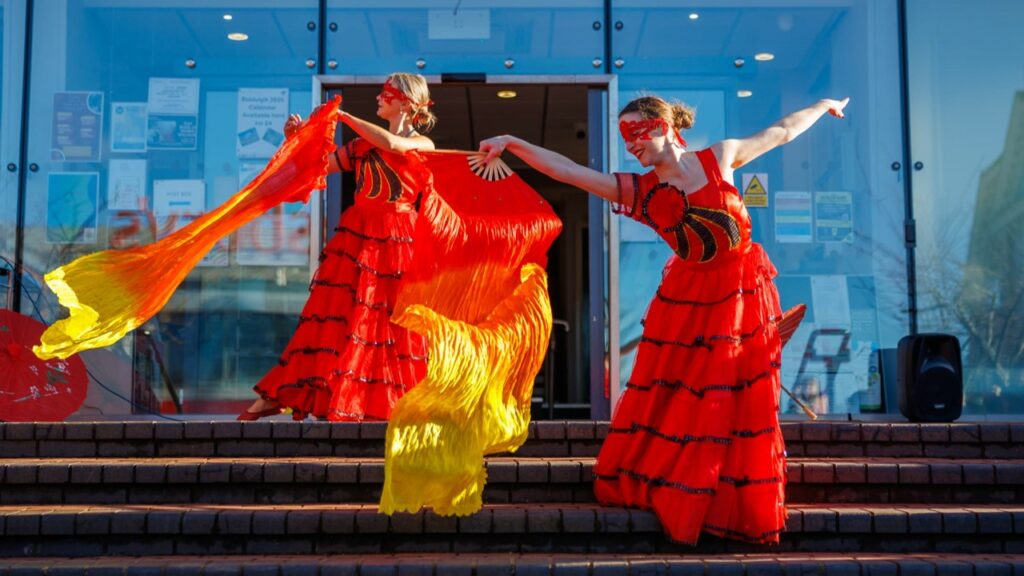 Two dancers in vibrant costume performing on the steps of the Town Hall