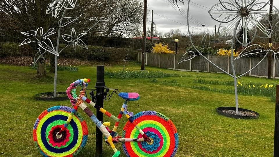 A cycle decorated by Biddulph Yarnbarms next to the Clematis Artwork in Biddulph