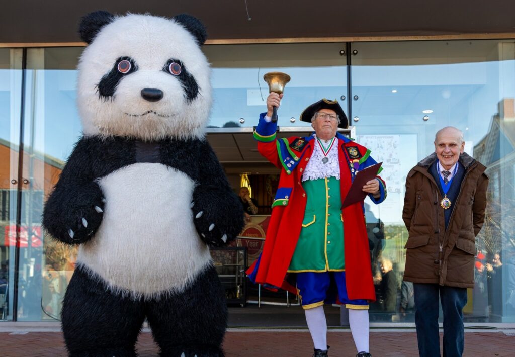A photo of Pom Pom the Giant Panda, John Robinson, the Town Crier and Town Mayor, Councillor Adrian Lawton opening the event on the Town Hall steps