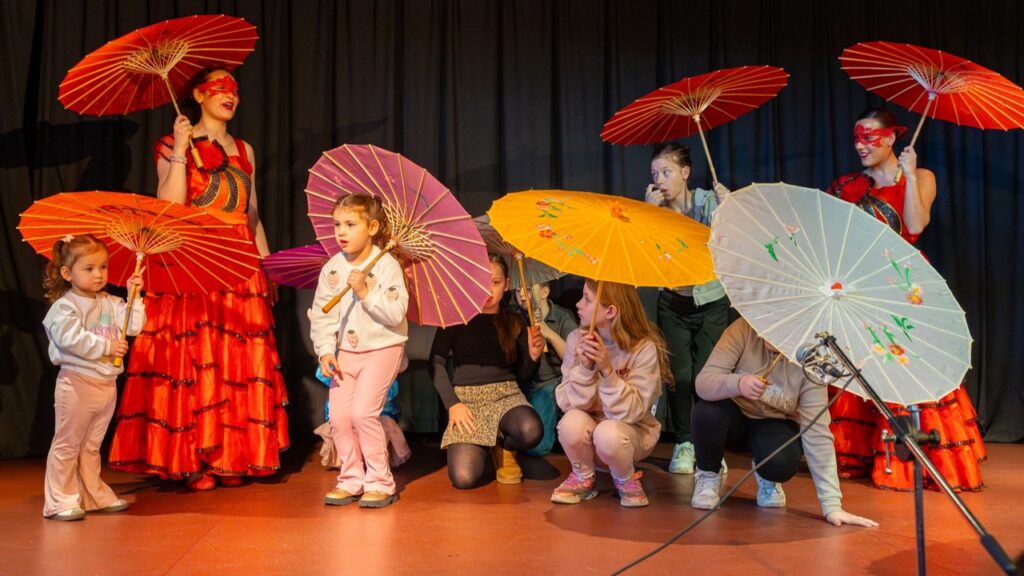 Umbrella dancers with children from the audience with umbrellas
