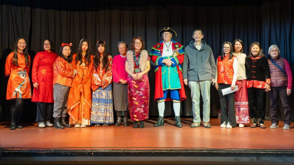 A group photo of the Chinese fellowship group with the town's Town Crier, John Robinson on the Town Hall stage