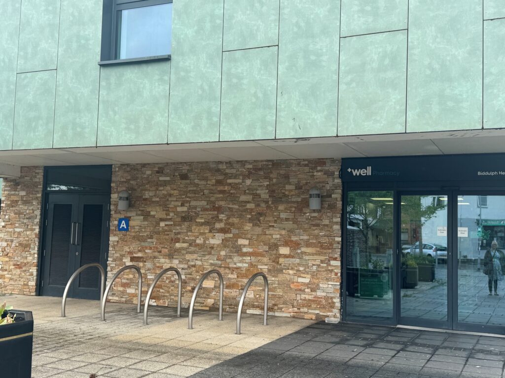 cycle racks outside the pharmacy on wharf road in front of the wall to the left of the entrance