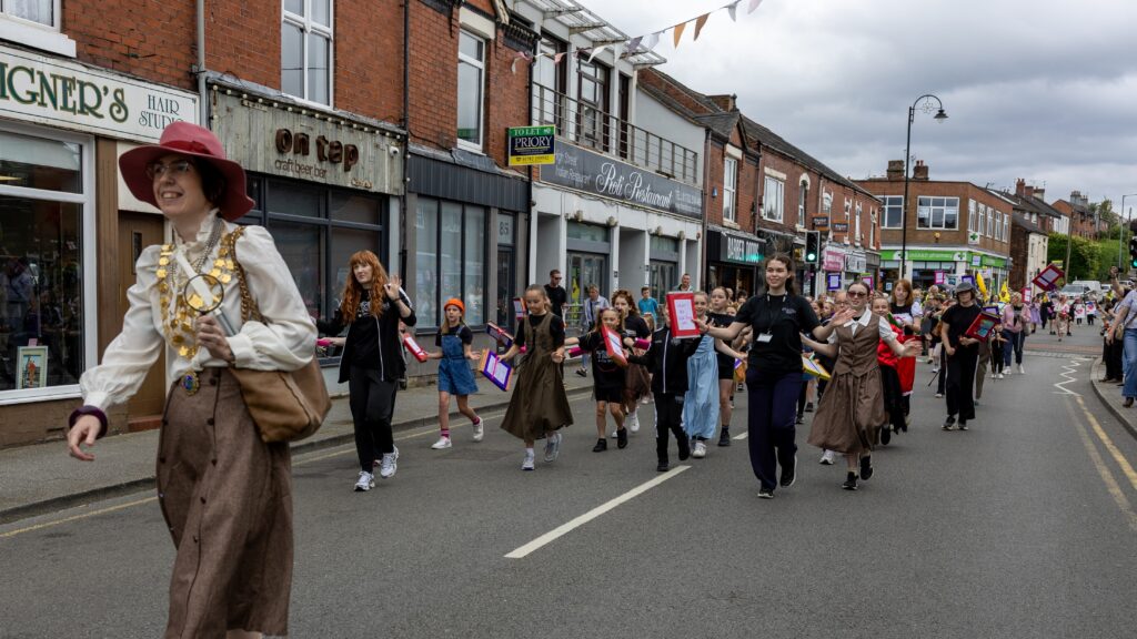 A scene of the parade walking down the High Street with the Mayor, Councillor Smith, at the front dressed as Miss Marple