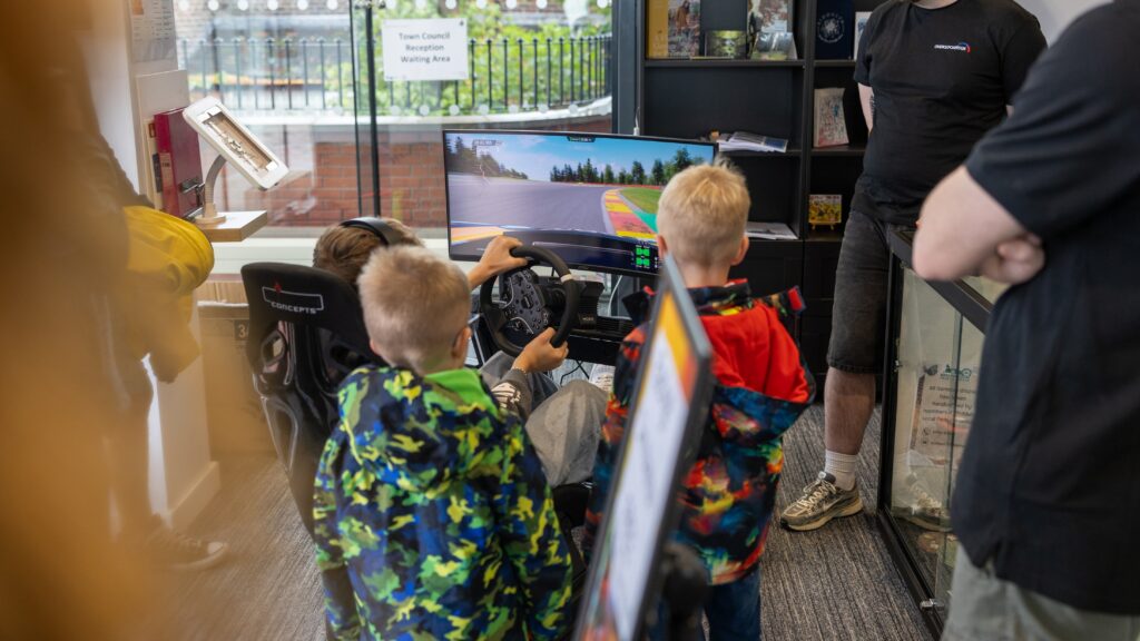 3 young childen playing on the simulator in the Town Hall foyer